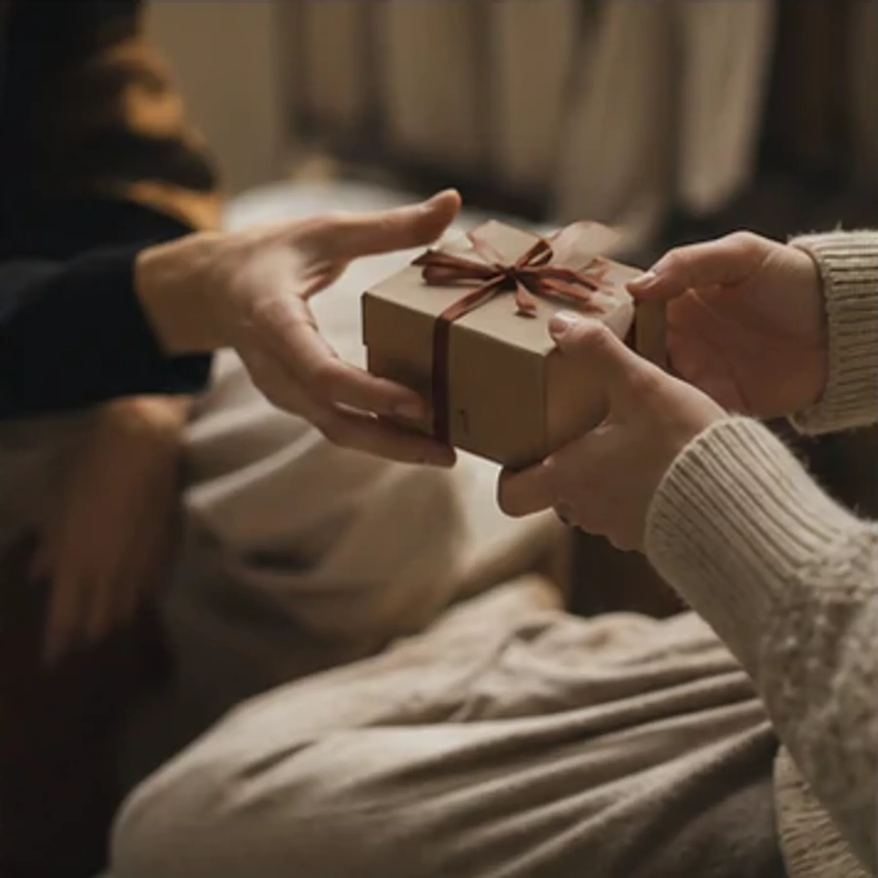 Two pairs of hands passing a wrapped parcel.